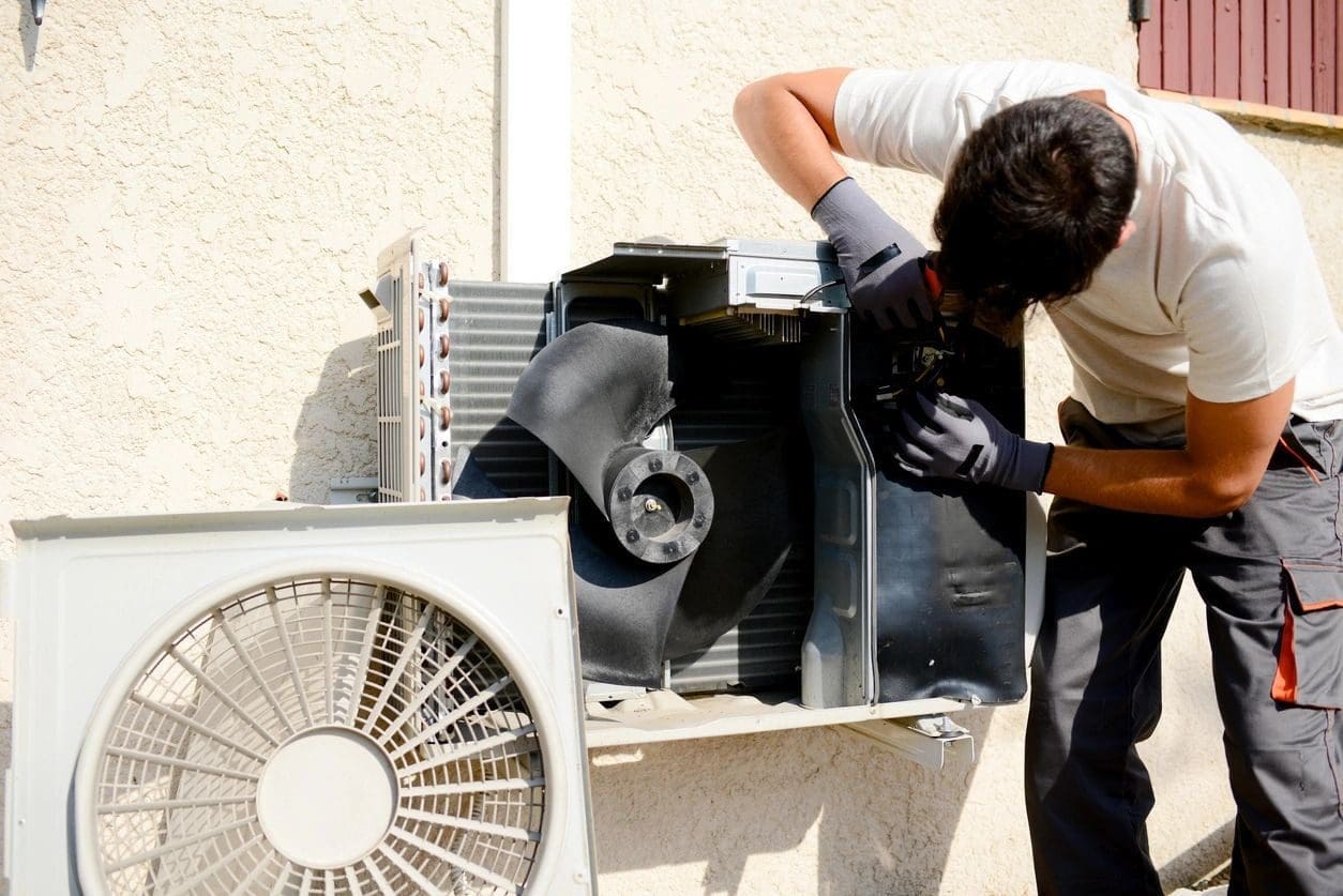 Air Conditioning Repair Technician Working on an AC Unit Outside An air conditioning repair technician is working on an air conditioner outside, possibly diagnosing or fixing the unit.