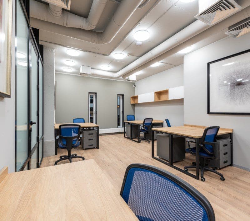A office space with many chairs and tables in it with exposed ac ducts