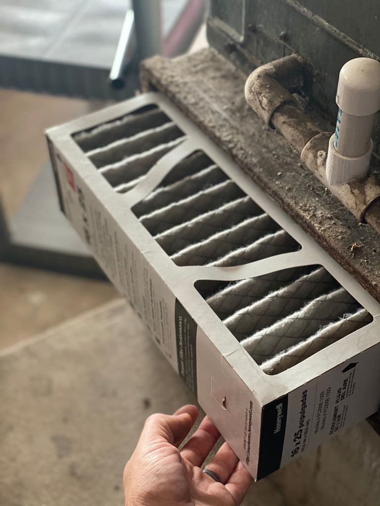 Person Inspecting the Air Filter on a Heater A person is inspecting the air filter on a heater, checking it for dirt or damage to ensure the system operates efficiently