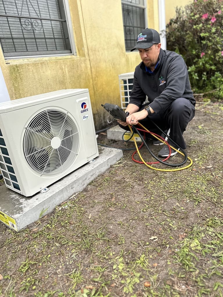 Service Technician Working on a Ductless Condenser Outside A service technician is working outside on a ductless air conditioner condenser, inspecting or repairing the unit to ensure it is functioning properly