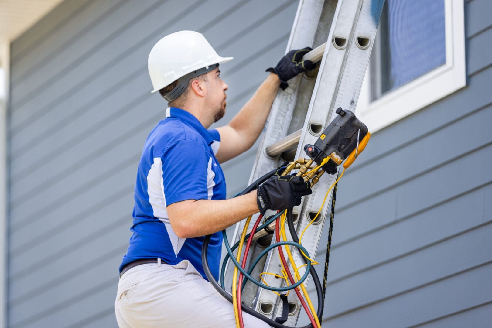 Commercial HVAC Technician Climbing Ladder to Service Rooftop Air Conditioning Unit A commercial HVAC service technician is climbing a ladder to reach and service an air conditioning unit mounted on the roof of a building, preparing for maintenance or repairs.
