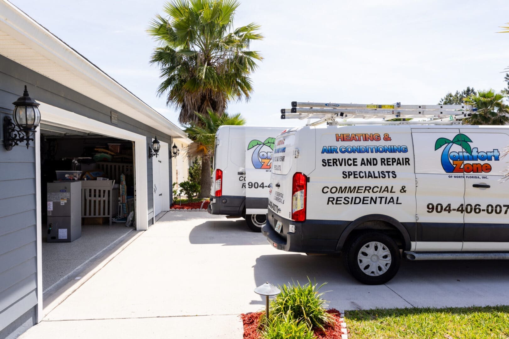 Comfort Zone of North Florida AC A couple of Comfort Zone of North Florida air conditioning vans parked in front of a house for an AC Install.