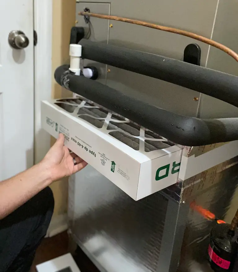 Air Filter Replacement A person is holding the air conditioner filter at the ac unit during a routine service