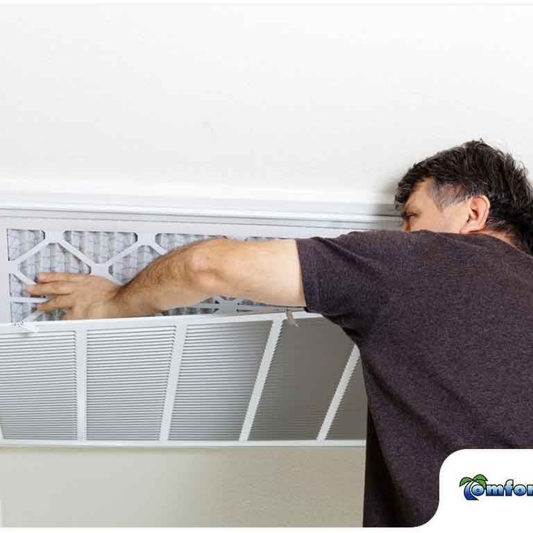 A Comfort Zone of North Florida heating and cooling technician is checking an air conditioning filter in the ceiling during a routine maintenance service