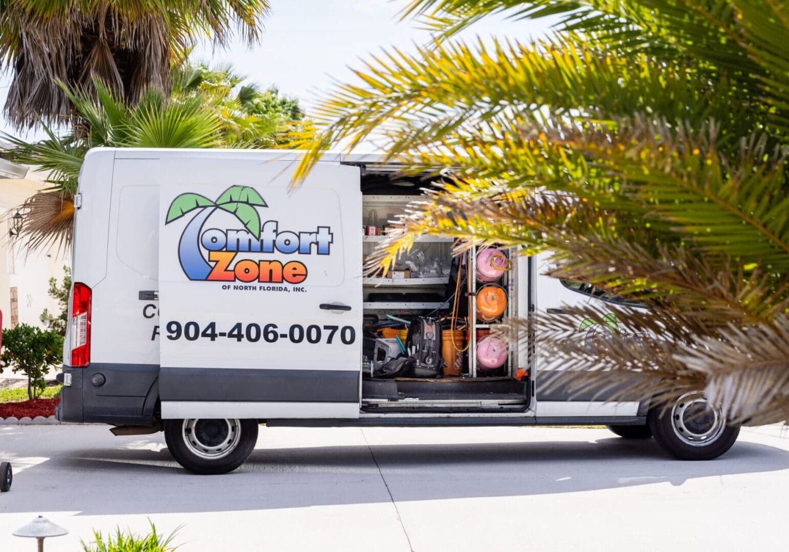 Air Conditioning Service Truck in Scenic Nocatee, Florida A white air conditioning service truck with company branding is parked on a sunny street, with tall palm trees and a Nocatee, Florida neighborhood visible in the background.