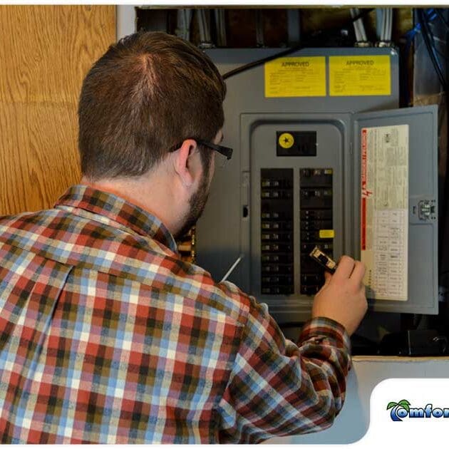An electrical serviceman is inspecting a circuit panel box, checking for any issues or maintenance needs to ensure safe operation