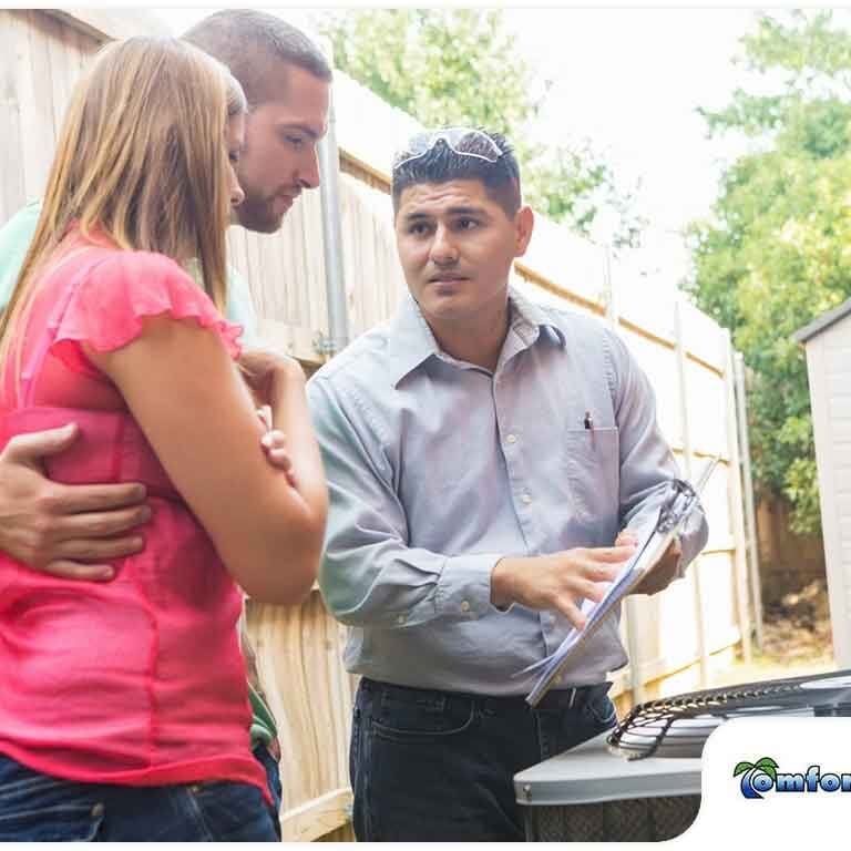 Air Conditioning Service Man Educating Homeowners About a Condenser An air conditioning service man is educating homeowners about a condenser, explaining its role in the cooling system and how it operates for optimal performance