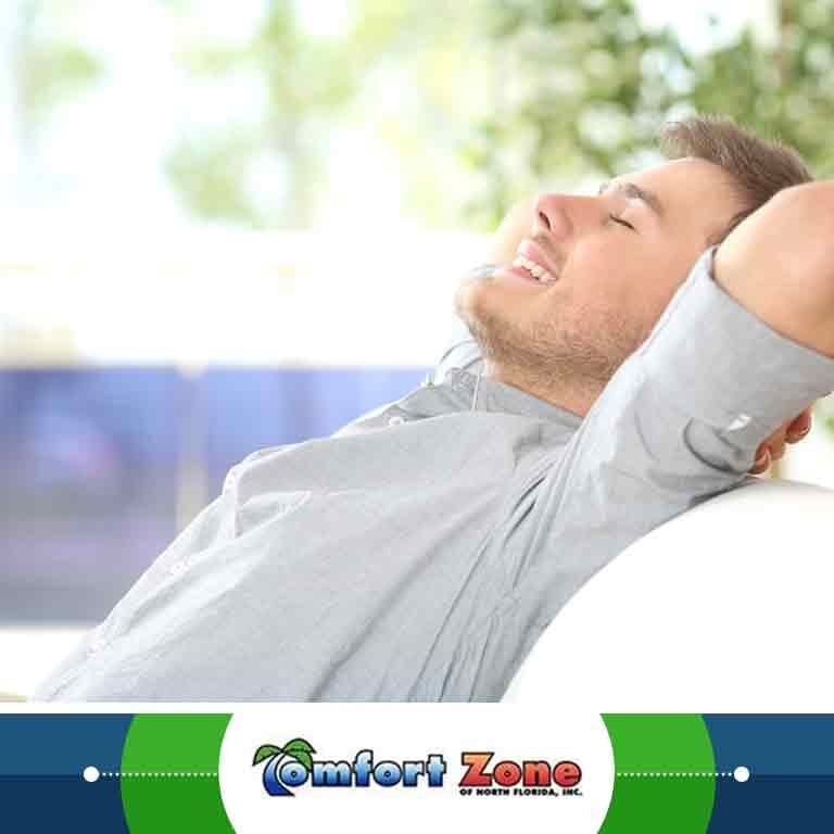A homeowner is sitting comfortably on a couch with his arms raised, enjoying a relaxed and cozy moment