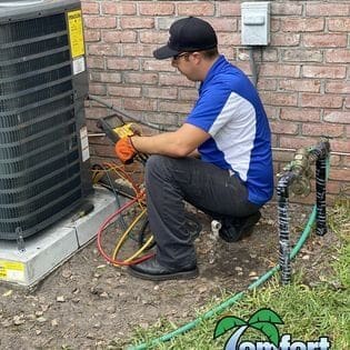 A HVAC Technician is working on an outdoor air conditioner, using tools to inspect or repair the unit for optimal performance in Nassau County