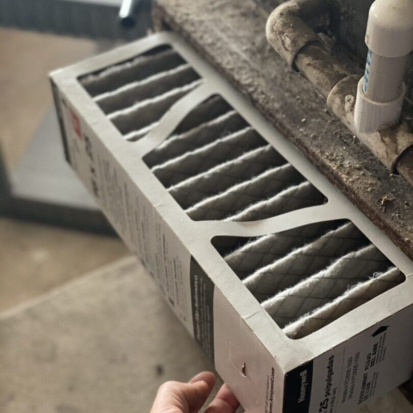 A person is holding a portable heater in their hand, inspecting it for use or maintenance, with a neutral indoor background
