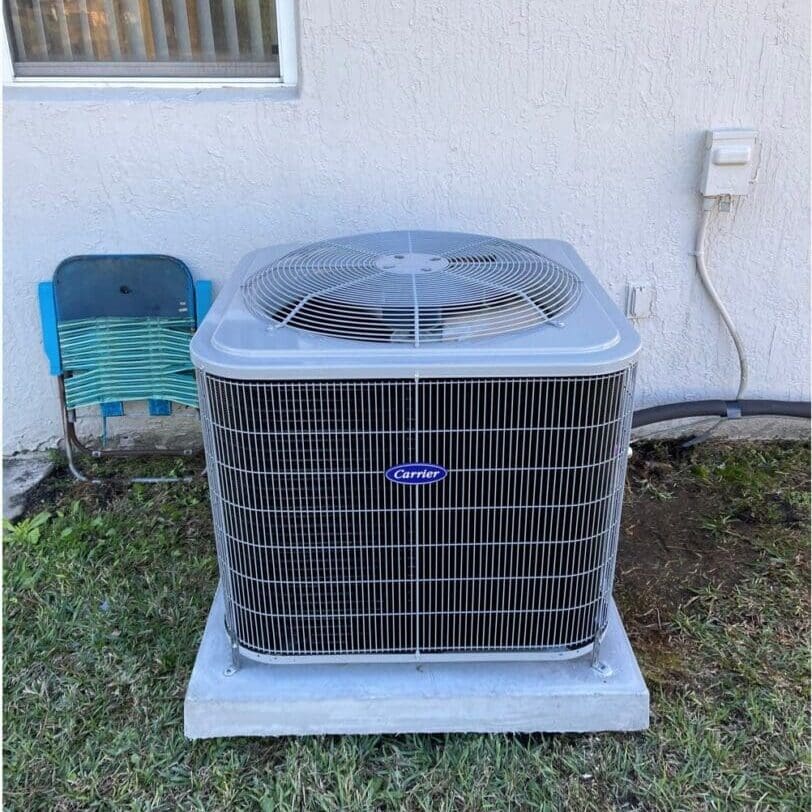 A large air conditioner is installed outside a house, placed on a concrete slab, ready for operation to cool the home efficiently