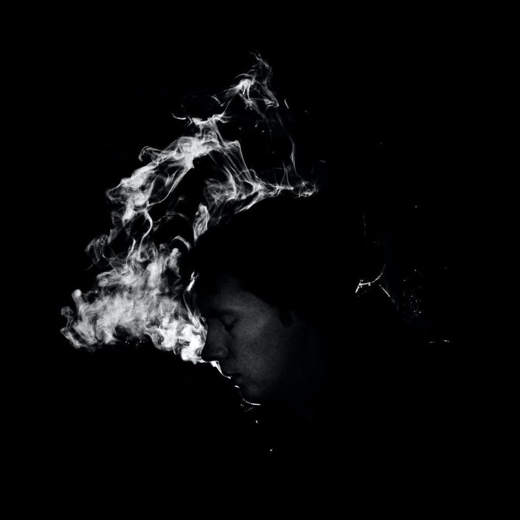A black and white photo showing smoke coming out from the top, possibly from a chimney or exhaust vent, creating a dramatic effect