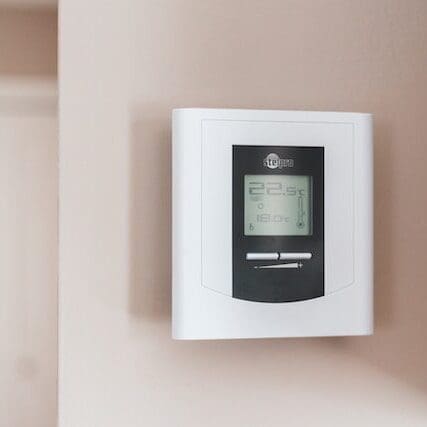 A white wall-mounted thermostat is positioned on the side of a room, providing easy access for adjusting the room's temperature
