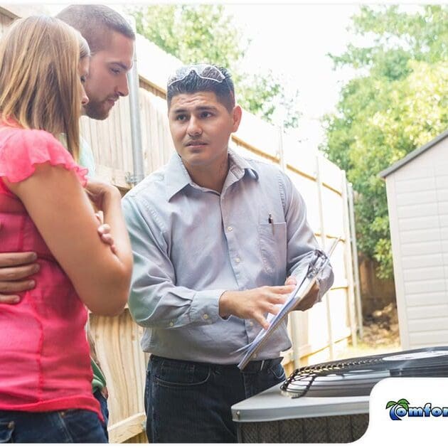 Air Conditioning Service Man and Homeowners Reviewing New Heat Pump Installation An air conditioning service man and the homeowners are going over the details of the newly installed heat pump, discussing its operation and benefits