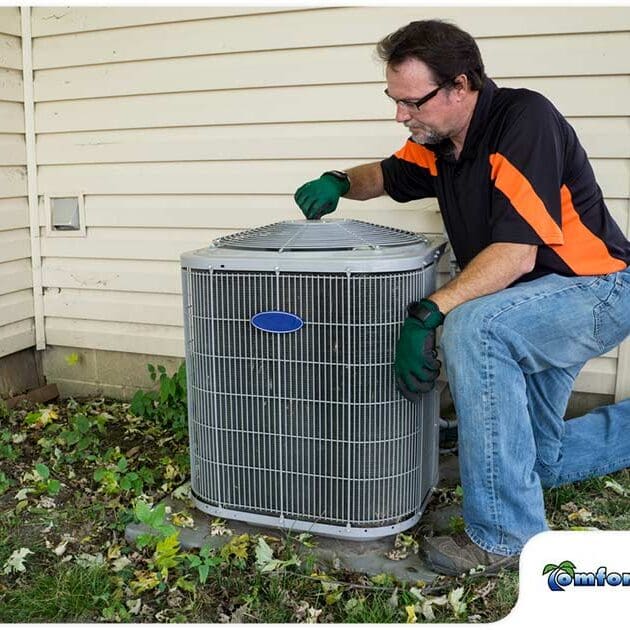 An residential AC service technician is preparing to service a Carrier air conditioning condenser, getting ready for maintenance or repairs to ensure its efficiency
