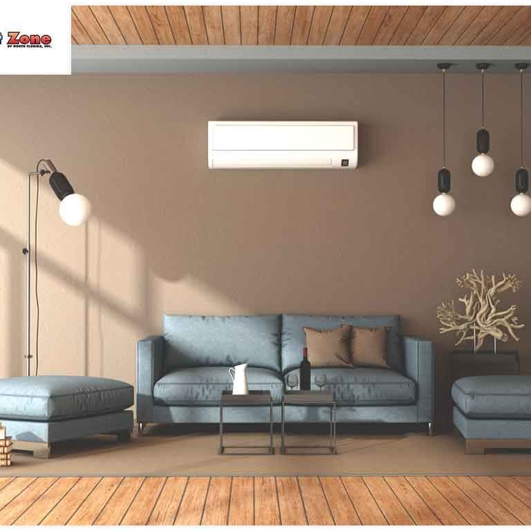 A living room with a couch, two lamps, and a ductless air conditioning unit mounted on the wall, providing cooling and comfort in the space