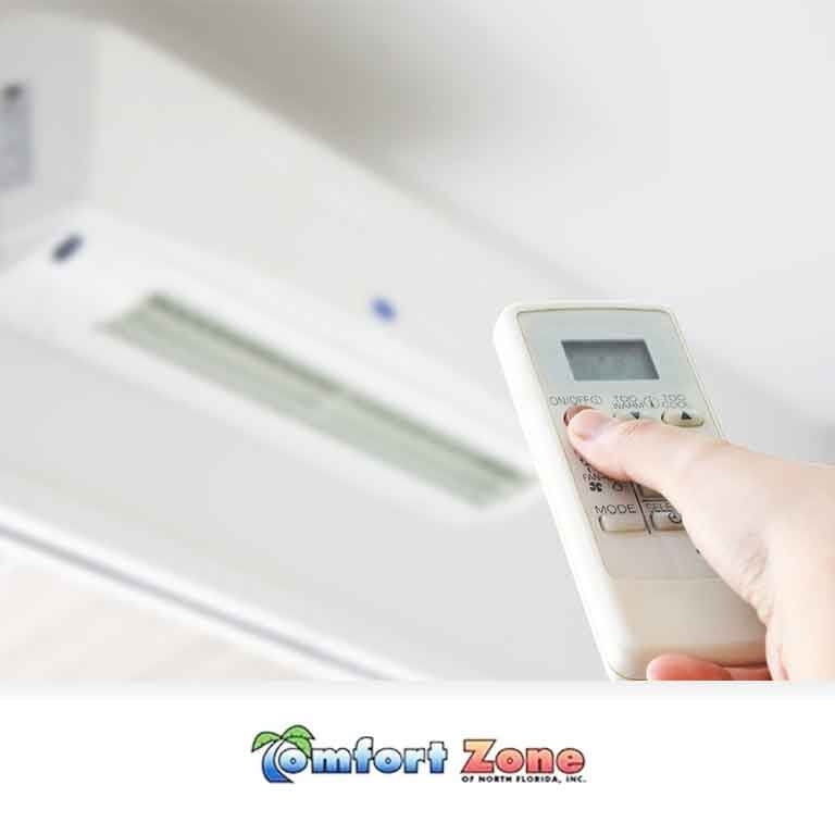Homeowner Adjusting Mini Split Temperature with Remote Control A homeowner is adjusting the temperature of a mini split air conditioning system using a remote control, customizing the indoor climate for comfort