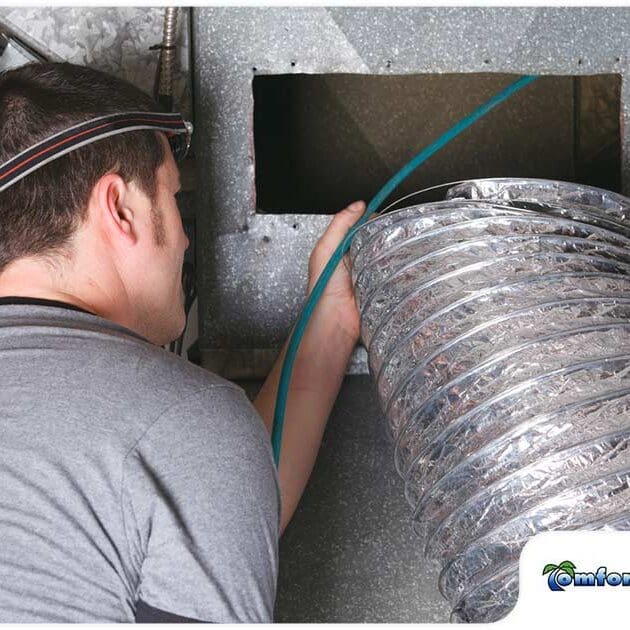 An AC technician is repairing a noisy furnace duct vent, addressing the issue to restore quiet operation and efficiency