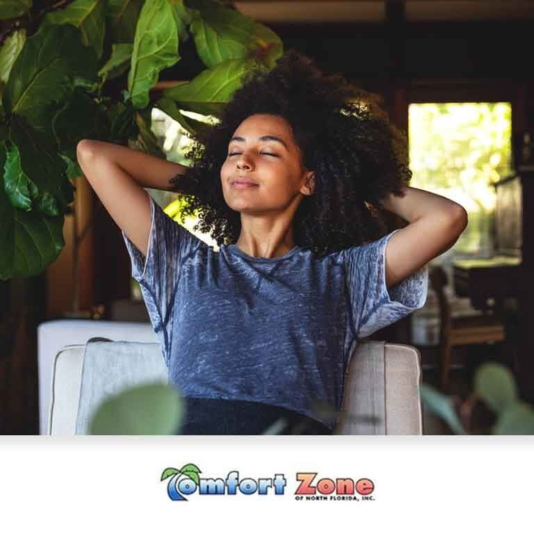 Woman Sitting in a Chair Relaxing A woman is sitting in a chair with her hands behind her head, relaxing in a comfortable indoor environment
