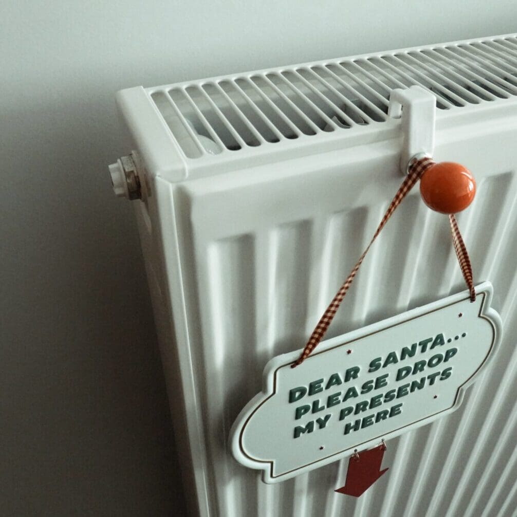 A heating radiator with a sign hanging on it, possibly indicating instructions or a warning related to the radiator’s use